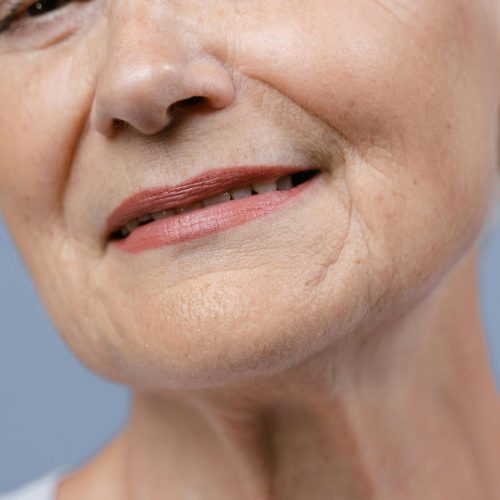 Detailed close-up of an elderly woman's lips and skin, showcasing natural wrinkles.